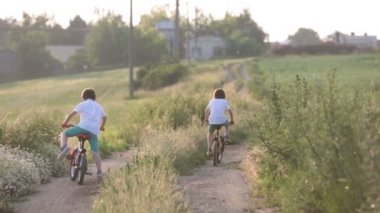 Sportif çocuk, erkek kardeşler, Bisiklet üzerinde bir kırsal manzara birlikte günbatımı üzerinde sürme.