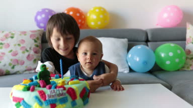 Sevimli çocuk, okul öncesi çocuk, renkli pasta, mumlar, evde balonlar ile onun Doğum günü kutluyor