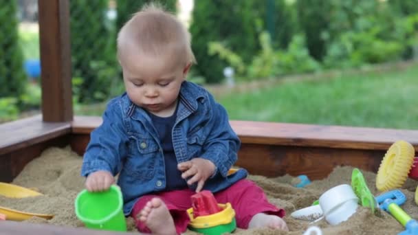 小さな男の子は 屋外のおもちゃで砂場で遊ぶ — ストック動画