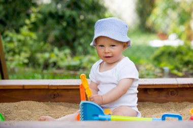 Bir sandpit açık havada oyuncakları ile oynarken küçük oğlu,