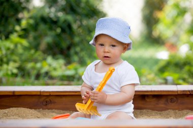 Bir sandpit açık havada oyuncakları ile oynarken küçük oğlu,