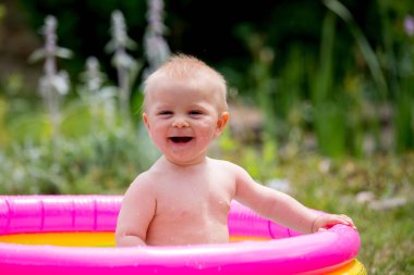 Arka bahçede, küçük bebek havuzda eğleniyor oynayan sevimli küçük çocuk, yürümeye başlayan çocuk,