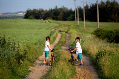 Sportif çocuk, erkek kardeşler, Bisiklet üzerinde bir kırsal manzara birlikte günbatımı üzerinde sürme