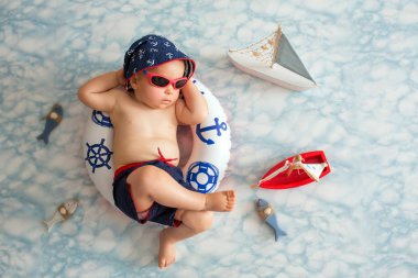 Mayo Şort ve güneş gözlüğü, Kapalı atış giyen sevimli yürümeye başlayan çocuk, bir küçük şişme yüzme yüzüğü, Uyuyan erkek bebek