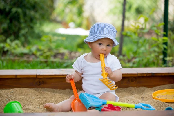 Bir sandpit açık havada oyuncakları ile oynarken küçük oğlu,