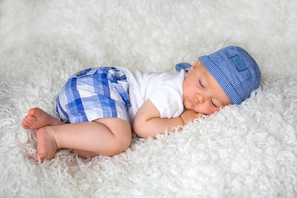 Cute baby boy, sleeping in bed with hat at home
