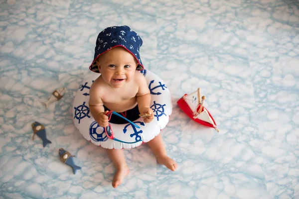 水着ショート パンツやサングラス 屋内撮影を着て小さな浮き輪に横たわってかわいい赤ちゃん男の子 — ストック写真