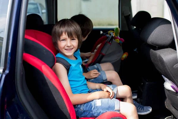 Little baby boy and his older brothers, traveling in car seats, going on a holiday, traveling on the back seat