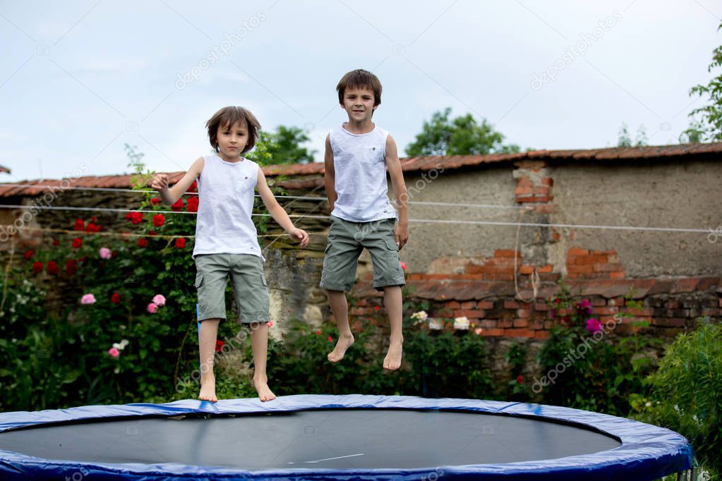 SCute children, brothers, jumping on a trampoline in garden, summertime