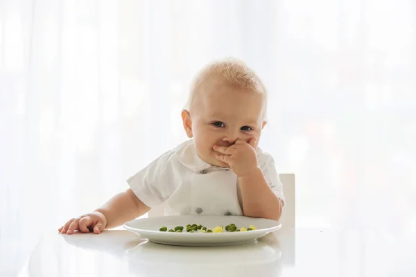 幼儿的孩子 可爱的男孩在白色衬衫 吃豌豆在家里 回来点燃 — 图库照片
