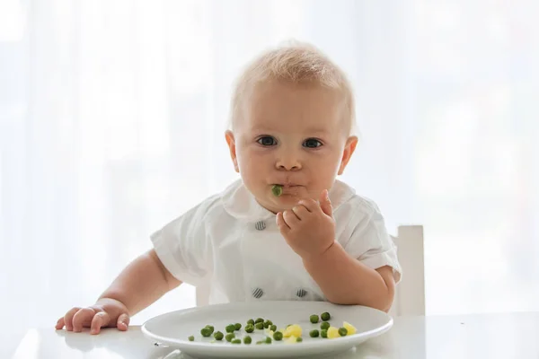 幼儿的孩子 可爱的男孩在白色衬衫 吃豌豆在家里 回来点燃 — 图库照片