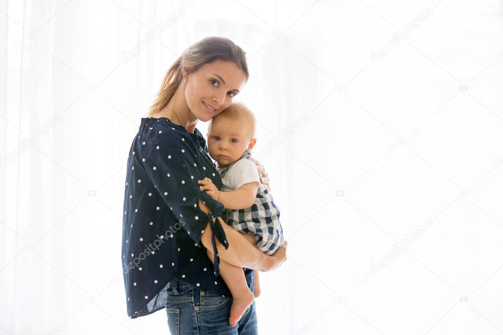 Mother, holding her sick baby boy, sad baby, isolated on white background