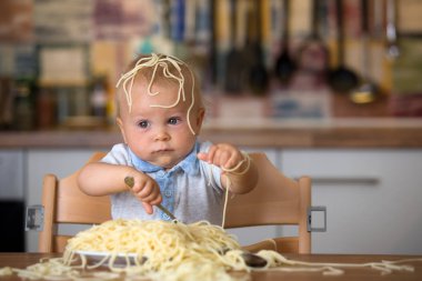 Küçük oğlu, yürümeye başlayan çocuk, spagetti yemek için yemek ve mutfak evde bir karışıklık yapmak