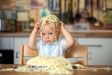 Küçük oğlu, yürümeye başlayan çocuk, spagetti yemek için yemek ve mutfak evde bir karışıklık yapmak