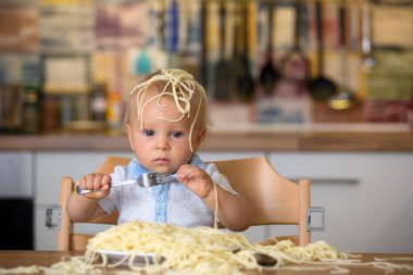 Küçük oğlu, yürümeye başlayan çocuk, spagetti yemek için yemek ve mutfak evde bir karışıklık yapmak