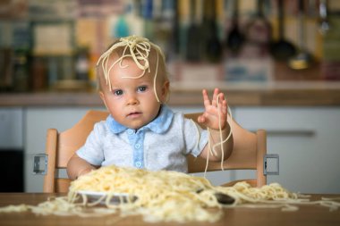 Küçük oğlu, yürümeye başlayan çocuk, spagetti yemek için yemek ve mutfak evde bir karışıklık yapmak