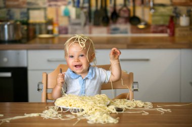 Küçük oğlu, yürümeye başlayan çocuk, spagetti yemek için yemek ve mutfak evde bir karışıklık yapmak