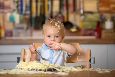 Küçük oğlu, yürümeye başlayan çocuk, spagetti yemek için yemek ve mutfak evde bir karışıklık yapmak