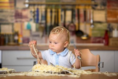 Küçük oğlu, yürümeye başlayan çocuk, spagetti yemek için yemek ve mutfak evde bir karışıklık yapmak
