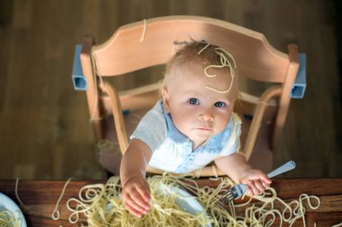 Küçük oğlu, yürümeye başlayan çocuk, spagetti yemek için yemek ve mutfak evde bir karışıklık yapmak