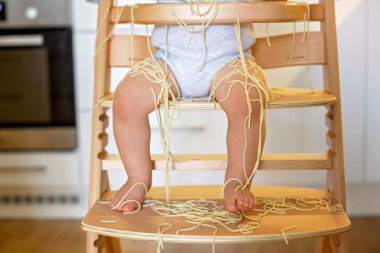 Küçük oğlu, yürümeye başlayan çocuk, spagetti yemek için yemek ve mutfak evde bir karışıklık yapmak