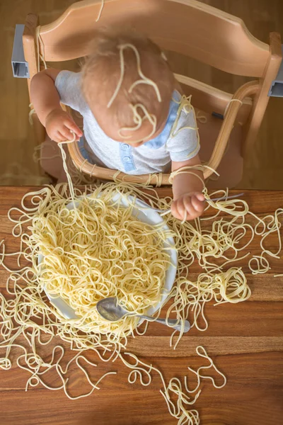 Küçük oğlu, yürümeye başlayan çocuk, spagetti yemek için yemek ve mutfak evde bir karışıklık yapmak