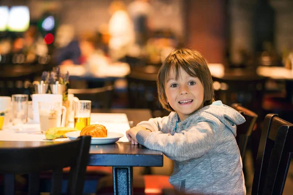 小さな男の子 クロワッサンを食べてホテルのレストランで朝食を楽しむ — ストック写真