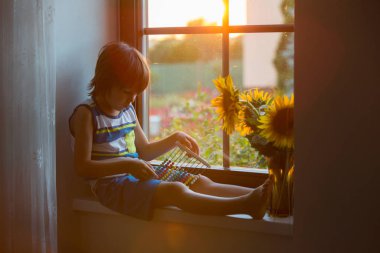 Abaküs ile bir pencere üzerinde günbatımı üzerinde oynayan sevimli küçük yürümeye başlayan çocuk