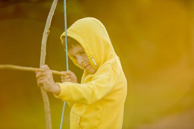 Okul öncesi çocuk, ok ve yay ile bahçede günbatımı üzerinde çekim