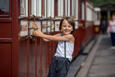 Güzel çocuk, giyinmiş vintage giysiler içinde eski buharlı tren sıcak yaz günlerinde İngiltere'de zevk.