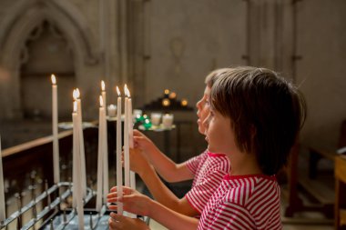 Küçük çocuk dua ediyor ve Ortodoks Kilisesi, iman ile üzgün çocuk bir mum koyar