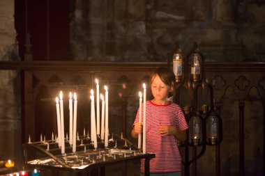 Küçük çocuk dua ediyor ve Ortodoks Kilisesi, iman ile üzgün çocuk bir mum koyar