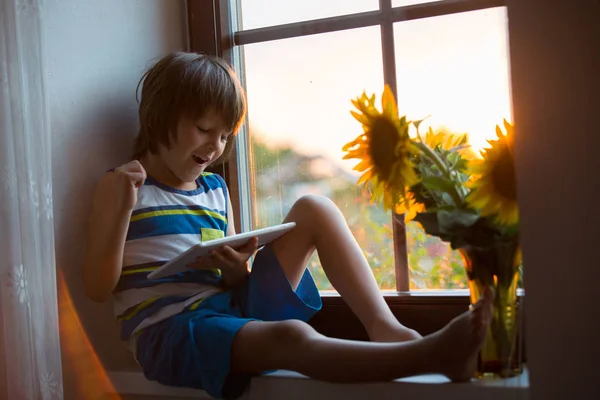 Criança Pequena Bonito Jogando Tablet Uma Janela Pôr Sol — Fotografia de Stock