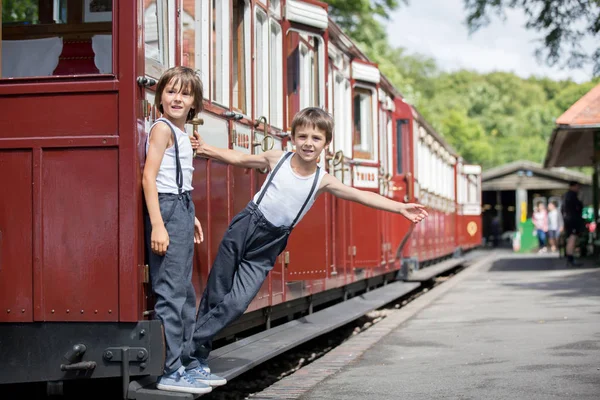 美しい子供 ビンテージの服を着て夏の暑い日にイングランドの古い蒸気機関車を楽しんで — ストック写真