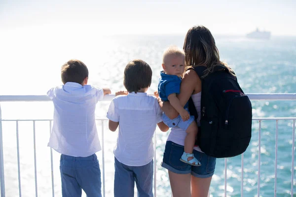 Happy family with children, enjoying the ship trip from the upper deck of the ship on a beautiful summer sunny day