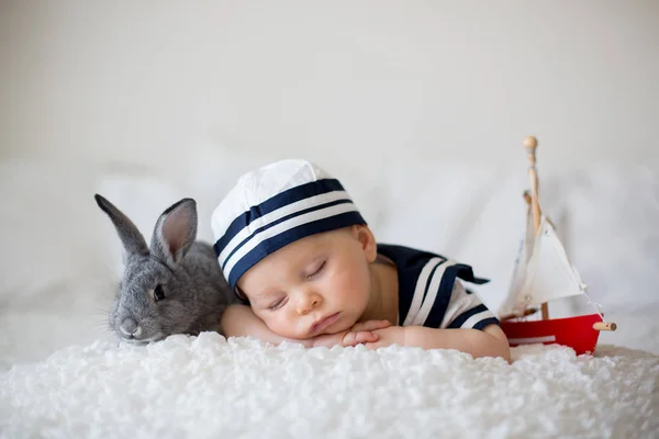 かわいい男の子服を着た海洋 木製ボートとかわいい赤ちゃんウサギの寝室で眠っています — ストック写真