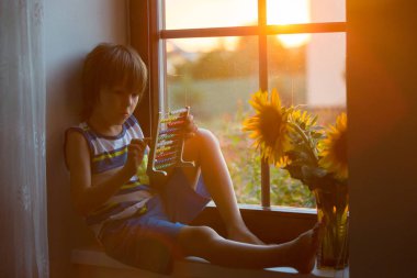 Abaküs ile bir pencere üzerinde günbatımı üzerinde oynayan sevimli küçük yürümeye başlayan çocuk