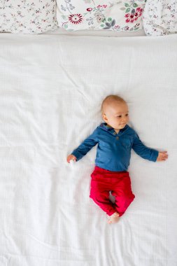 Yukarıdan sevgi ile yüksek açı çekim, sarılma, yatakta yatan anne ve yürümeye başlayan çocuk bebek çocuk. Mutlu aile concep