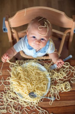 Küçük oğlu, yürümeye başlayan çocuk, spagetti yemek için yemek ve mutfak evde bir karışıklık yapmak