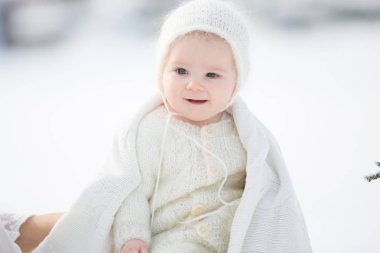 Beyaz elbiseli güzel bir anne ve örgü tulumlu şirin bir çocuk güneşli bir kış gününde güzel kış portrelerini çektiler.