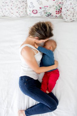 Anne ve bebek bebek çocuk, yatakta, emzirme onun yukarıdan sevgi ile yüksek açı çekim, sarılma yatıyor. Mutlu aile concep