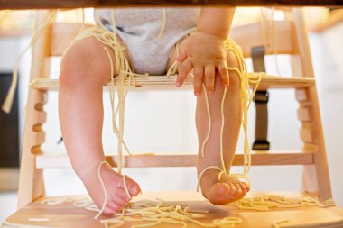 Küçük oğlu, yürümeye başlayan çocuk, spagetti yemek için yemek ve mutfak evde bir karışıklık yapmak