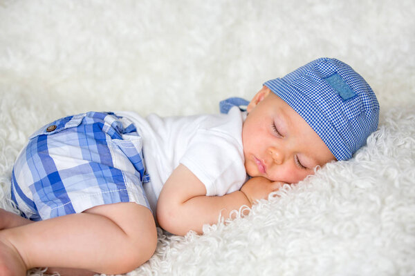 Cute baby boy, sleeping in bed with hat at home