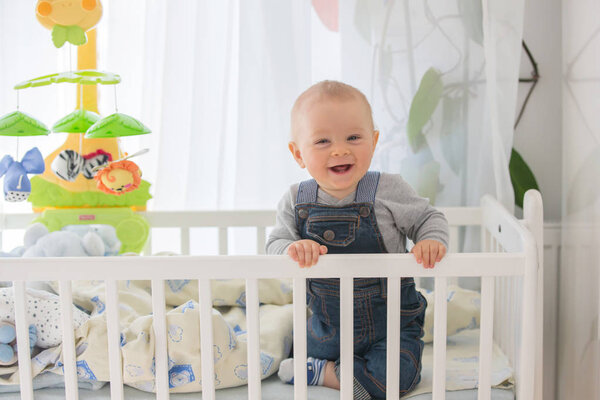 Smiling toddler boy, playing with little rabbit toy in crib, , smiling happily
