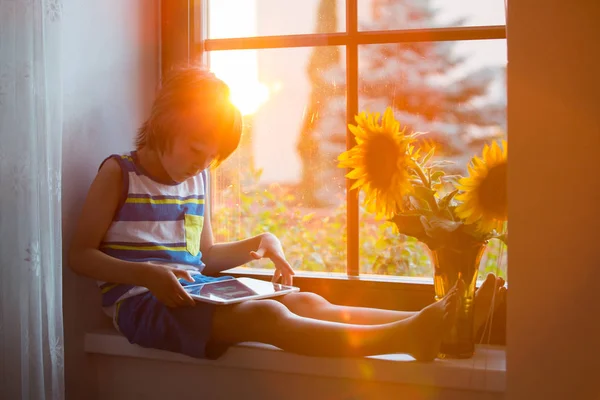 Schattige Kleine Peuter Kind Spelen Tablet Een Venster Zonsondergang — Stockfoto