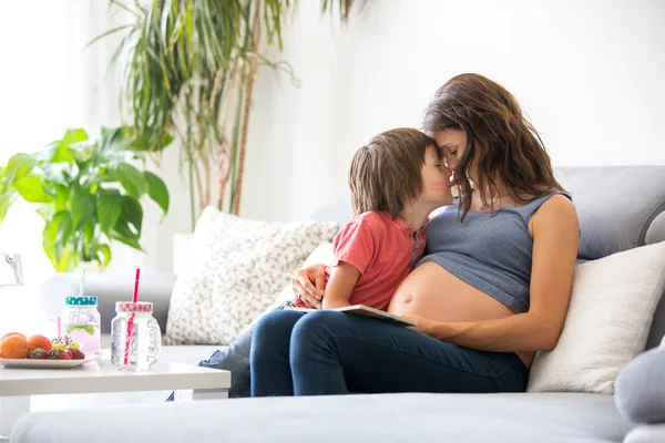 Genç hamile kadın, evinde bir kitabın sarılma ve gülüyor meyve, yemek oğlu için okuma