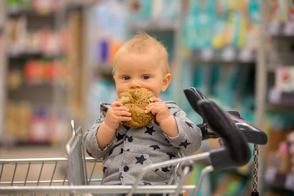 Niño Pequeño Sentado Carrito Compras Tienda Comestibles Sonriendo Comiendo Pan —  Fotos de Stock