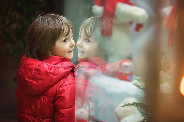 Schönes Kleines Kind Junge Sieht Weihnachtsdekoration Mit Spielzeug Einer Schaufenstervitrine — Stockfoto
