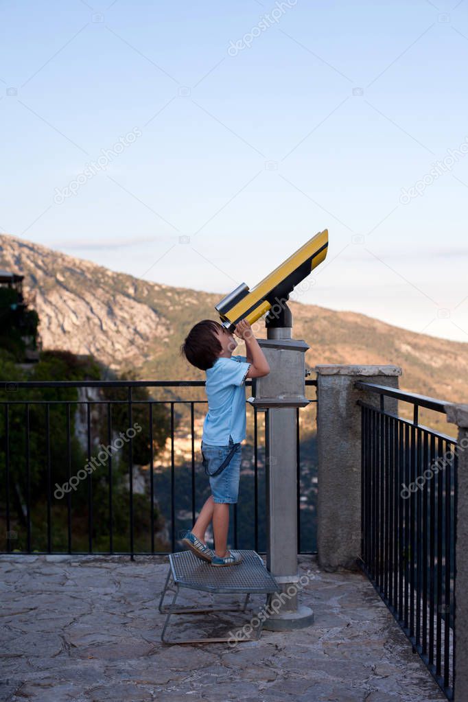 Curious boy, looking through a telescope at something interesting, summertime