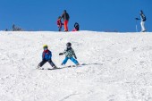 Dvě malé děti, sourozence bratry, lyžování v rakouských horách za slunečného dne, zimě, těší sportovní
